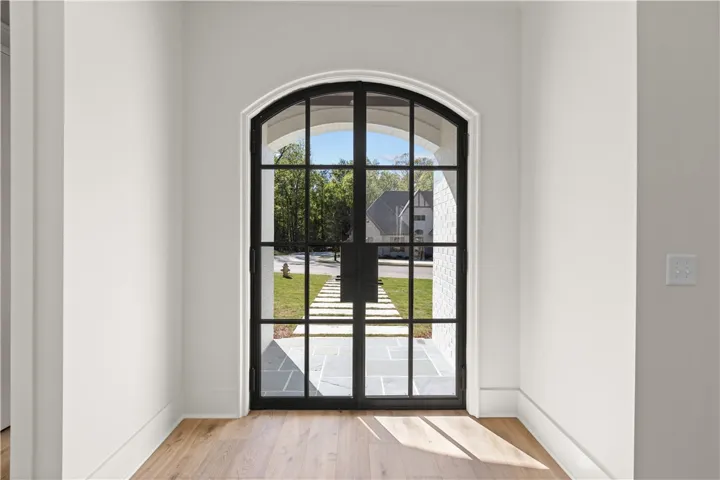 This bright entry features a grand archway with elegant glass panel doors.