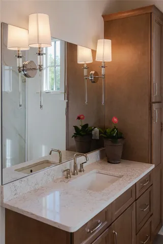 This bathroom features dual vanities with elegant sconce lighting.