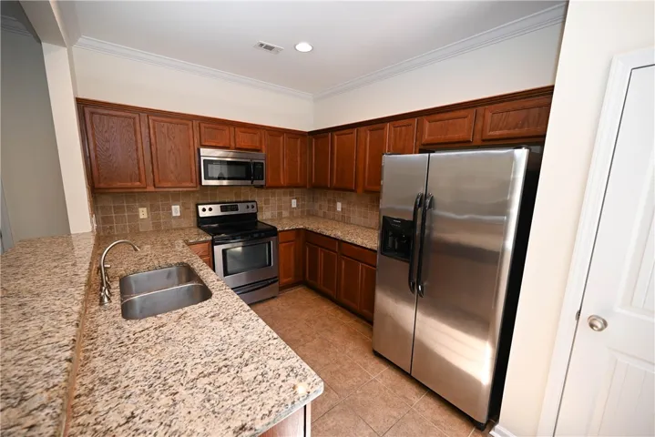 The kitchen includes a breakfast bar, tile backsplash and stainless steel appliances.