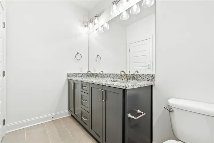 A well-appointed bathroom features a spacious double vanity with granite counters and tile flooring.