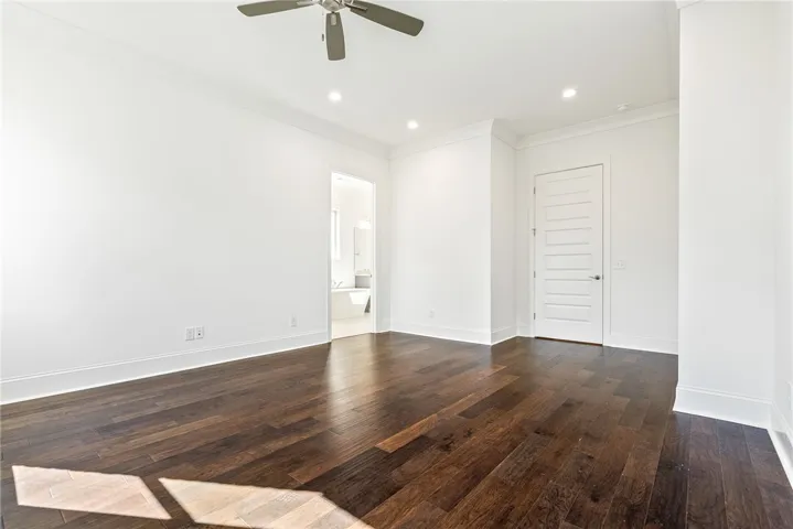 This spacious bedroom features elegant hardwood floors and convenient access to a primary bathroom.