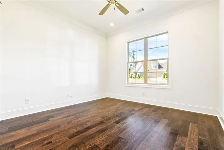 This versatile room features warm hardwood flooring, bright natural light, and a clean, spacious ambiance.