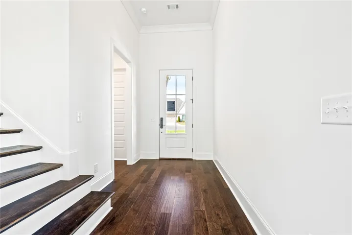Enter into a bright foyer with rich wood flooring and a classic white staircase.