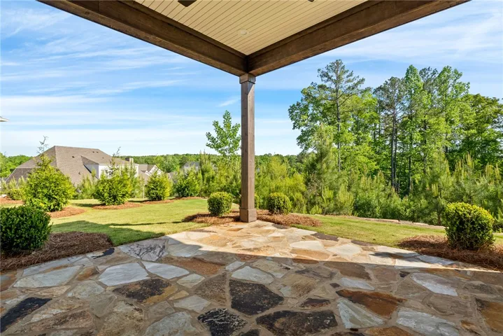 Enjoy outdoor living on this expansive stone patio, surrounded by lush landscaping and mature trees.