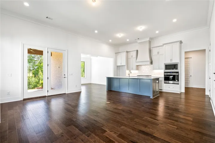 This expansive kitchen features an island, hardwood flooring, and direct outdoor access through elegant French doors.