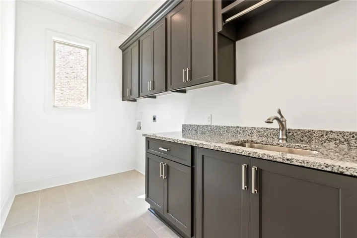 This laundry area features sleek cabinetry, a utility sink, and ample counter space for daily tasks.