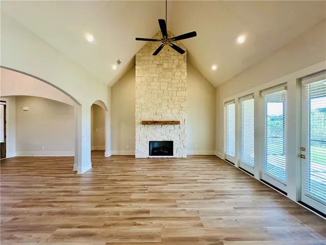 This expansive great room features a soaring vaulted ceiling and a stately stone fireplace, perfect for gatherings.