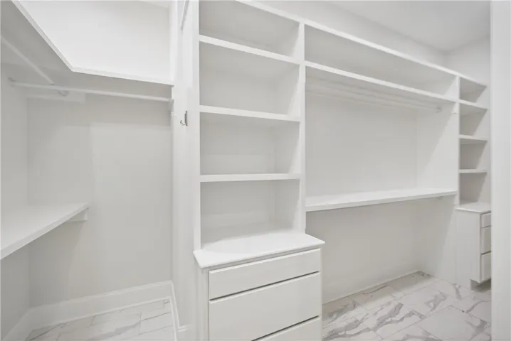 An organized walk-in closet boasts ample shelving and drawer space for all your storage needs.