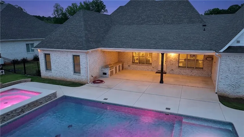 A spacious backyard oasis features an inviting pool, an adjacent spa, and a well-equipped outdoor kitchen.