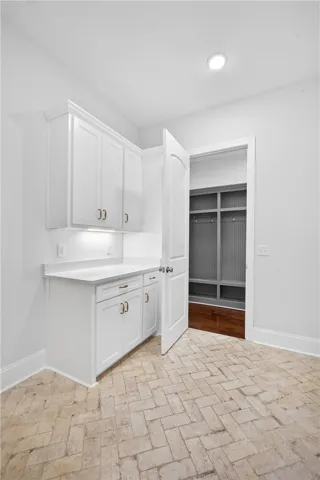 A well-appointed laundry area boasts crisp white cabinetry, durable flooring, and convenient access to a built-in storage unit.