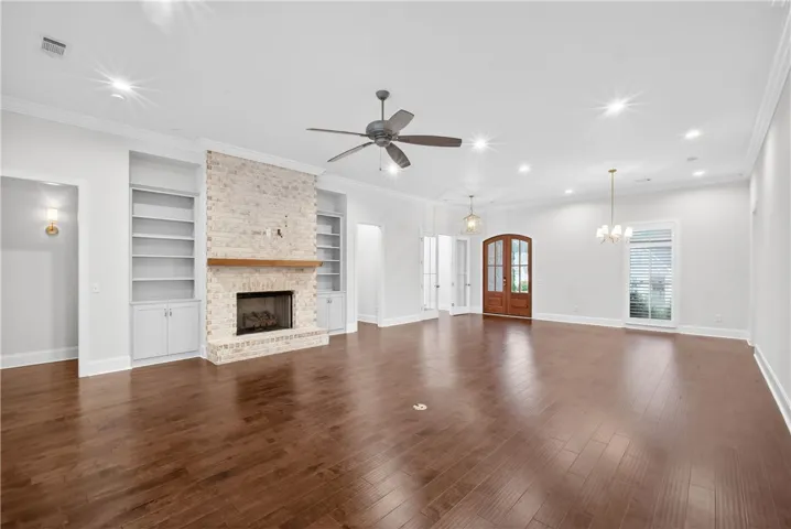 Rich hardwood flooring and a whitewashed brick fireplace create a refined ambiance in this spacious interior.
