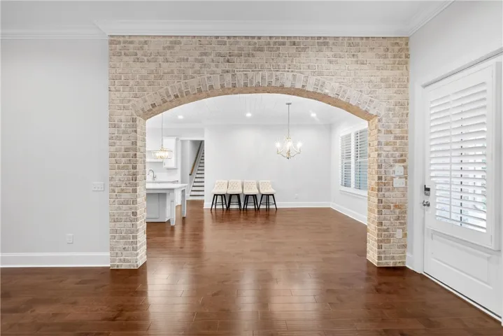 An inviting brick archway defines this home's well-lit open-concept living space with lustrous hardwood flooring.