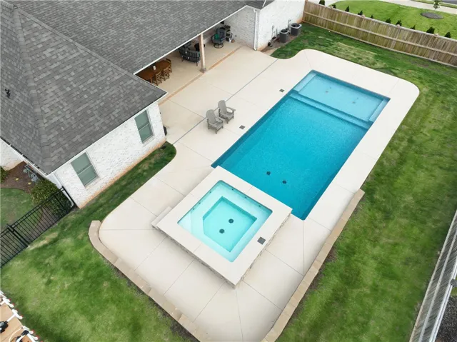 An inviting backyard oasis offers a sparkling pool and spa, complementing the outdoor living area.