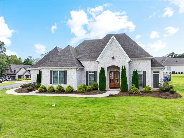 Elegant brick exterior with a welcoming arched entryway, framed by vibrant green landscaping.