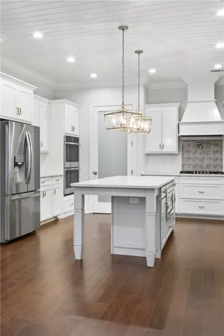 White cabinetry, an island, and sleek stainless appliances define this modern kitchen.