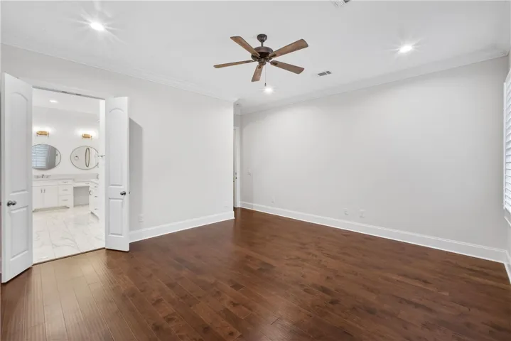 Rich hardwood flooring and recessed lighting define this inviting primary bedroom.