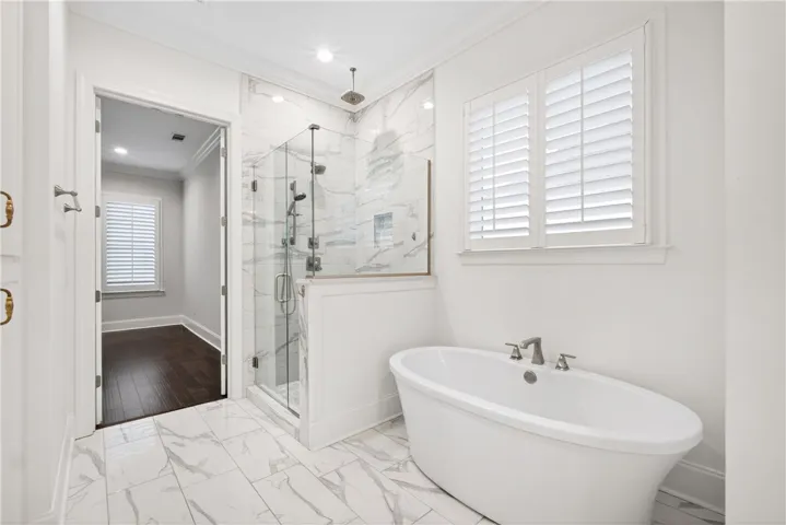 A refined primary bathroom featuring a freestanding soaking tub and a spacious glass-enclosed shower.