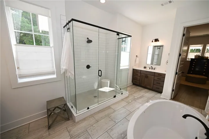 Primary bathroom with dual vanities, extra-deep soaking tub, oversized glass shower, & (of course!) more windows!! Back right: primary closet.