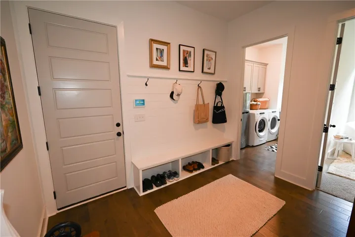 Mudroom with laundry in far right background, bedroom to right. Door to garage.