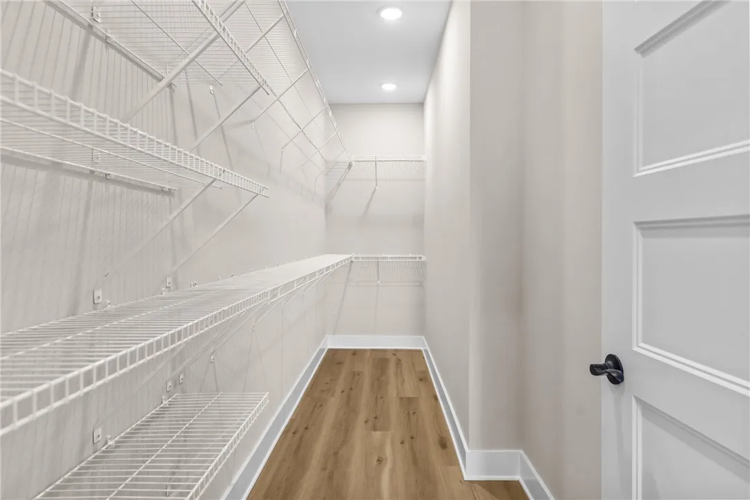 This spacious walk-in closet features ample wire shelving and beautiful hardwood flooring.