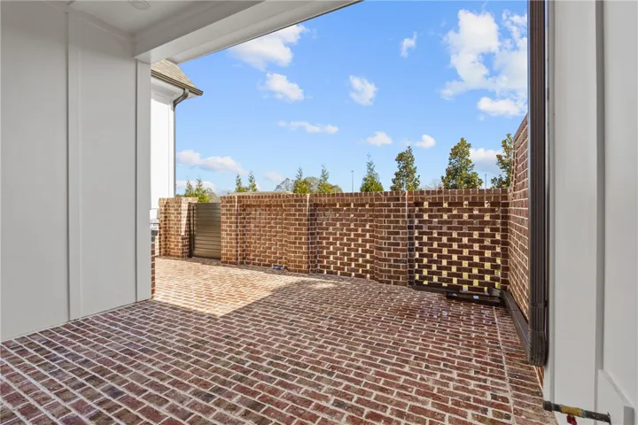 This private courtyard features durable brick paving and sturdy brick walls, creating a welcoming outdoor space.