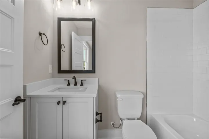 This bright bathroom features a modern vanity, sleek mirror, and pristine subway-tiled shower.