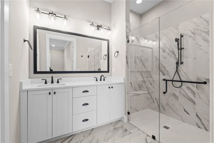 This primary bathroom features a dual vanity with ample storage and a sleek walk-in shower.