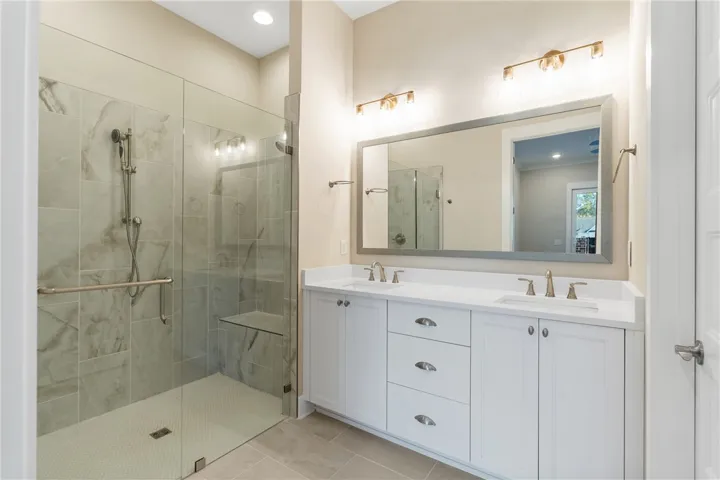 This spacious bathroom offers a double vanity and a glass-enclosed shower.