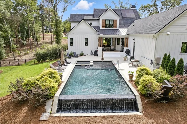 Black Pebble finished Infinity Pool with 8 person built in hot tub and a serene waterfall edge is overlooking breathtaking views of your very own Chewacla Creek!