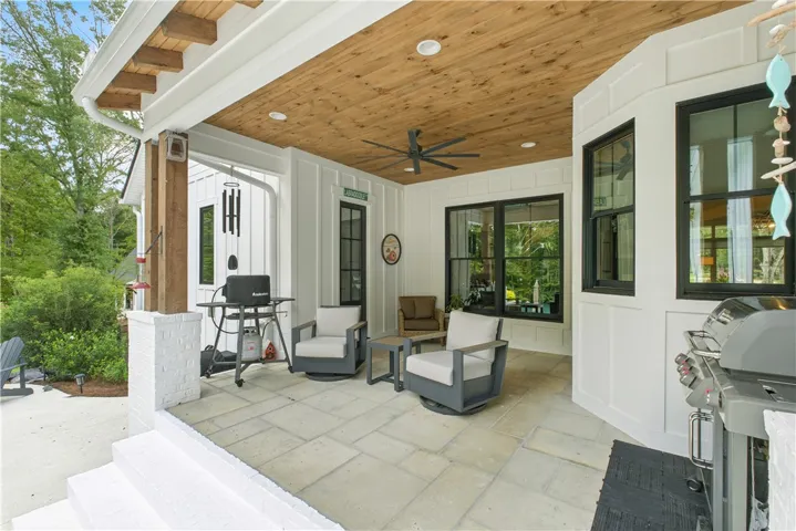 Covered back porch is the perfect place to enjoy views of the pool and the woods and creek beyond