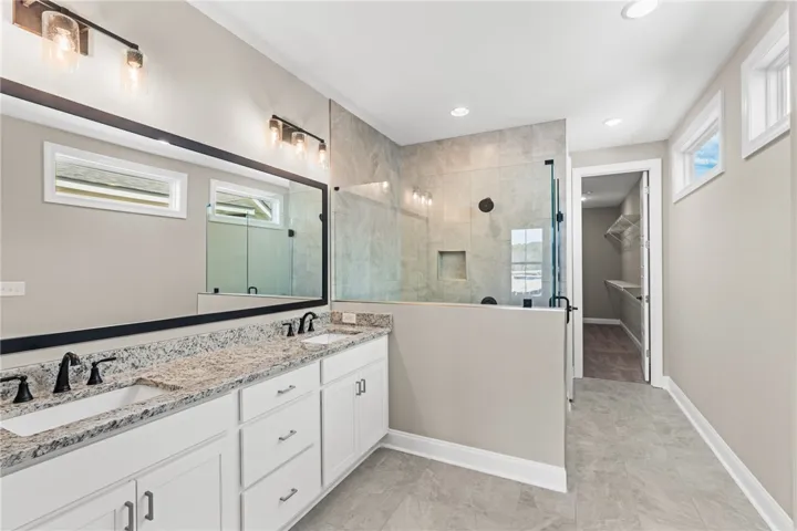 This spacious bathroom offers elegant finishes and a seamless transition to the primary closet.