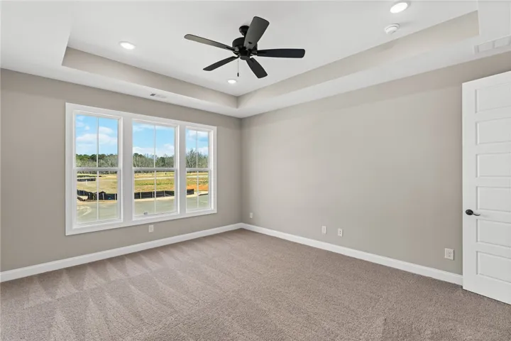 This spacious bedroom offers ample natural light and a serene view of the surrounding landscape.