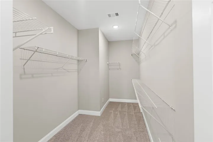 This spacious walk-in closet offers ample storage with versatile wire shelving and comfortable carpet flooring.