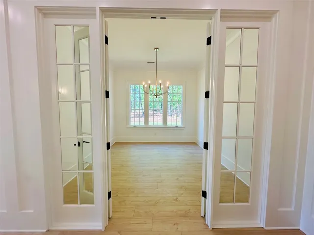 Step into this luminous space, featuring polished hardwood floors and expansive windows overlooking lush greenery.