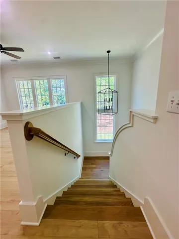 This inviting hardwood staircase leads to a lower level, illuminated by natural light.