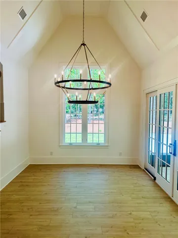 Bright, airy room with soaring ceilings, a striking chandelier, and a view of nature.