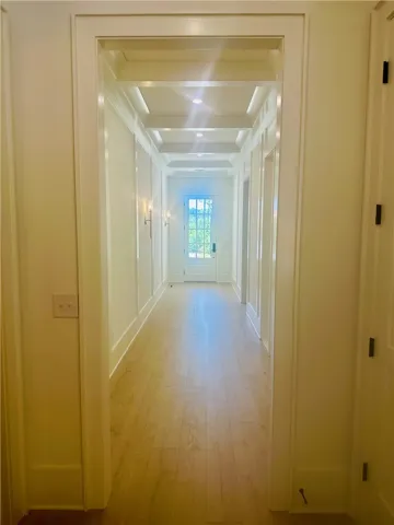 A long, inviting hallway features gleaming wood flooring and intricate ceiling details.