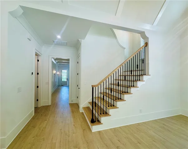 This bright hallway showcases a beautiful staircase leading to the upper level.