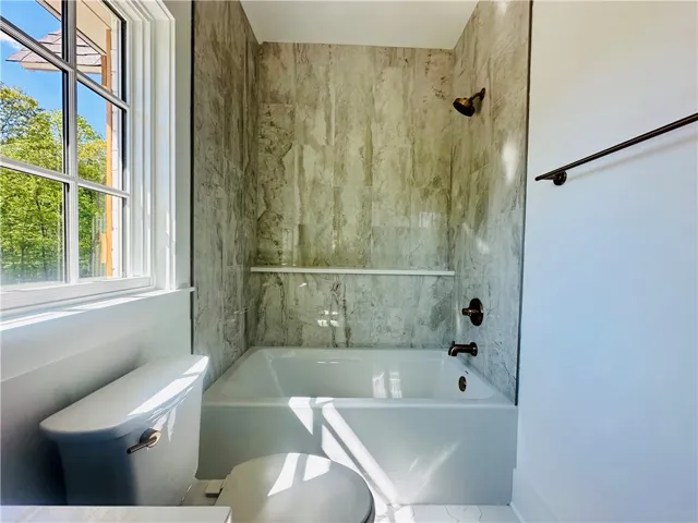 This bathroom features a sleek tub and shower combination with stylish wall tiling.