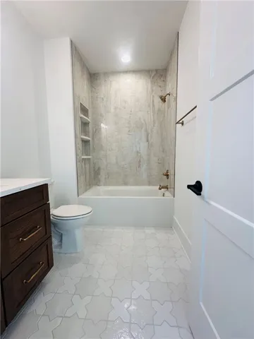 This bright bathroom features sleek tiling and a contemporary vanity, offering a fresh aesthetic.