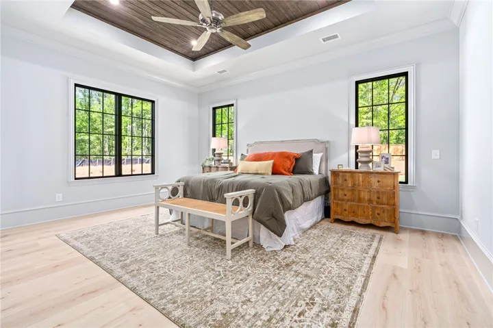 This spacious primary bedroom features rich wood ceiling details and abundant natural light.