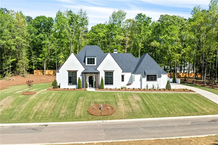 This charming residence features a pristine white brick exterior complemented by a verdant, expansive lawn.