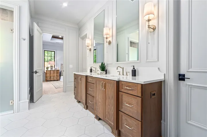 This spacious bathroom features dual vanities and elegant tile flooring, offering both style and functionality.