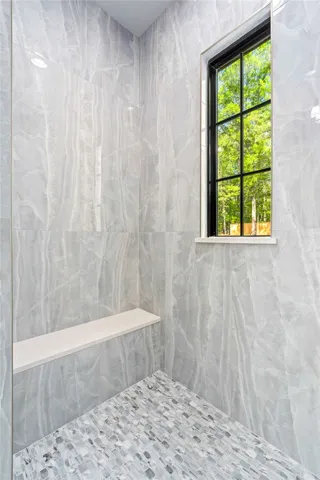 This tiled shower features a built-in bench and a window overlooking lush greenery.