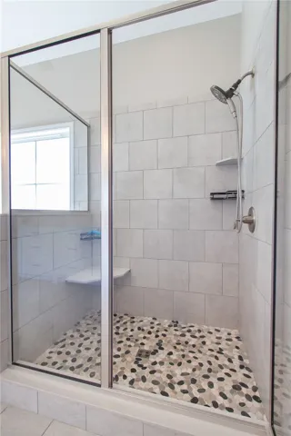 Shower with stone floor in primary bathroom