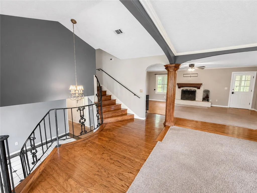 A grand entry with a sweeping staircase introduces a versatile living space with a classic fireplace.