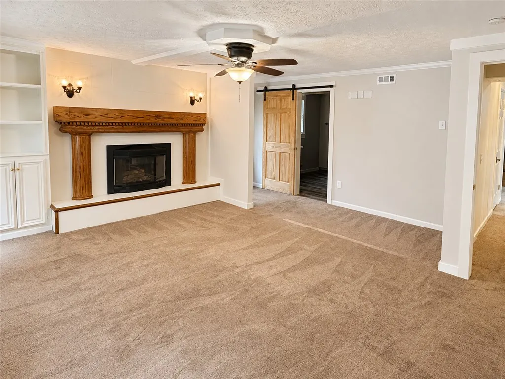 A comforting fireplace hearth with built-in cabinetry and a barn door entrance define this inviting living space.