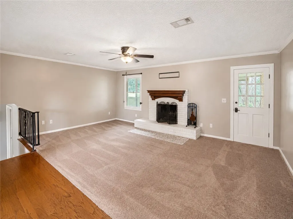 A well-lit living area features a charming fireplace with a brick hearth and a ceiling fan.