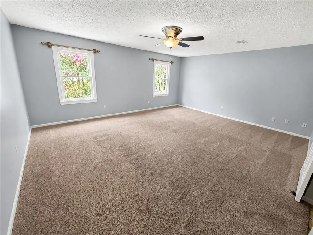 A spacious bedroom offers comfort with plush carpeting and natural illumination.