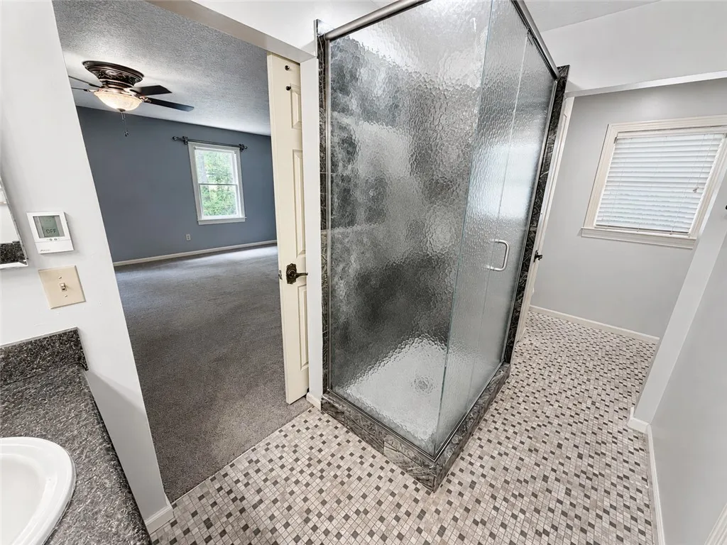 A well-appointed primary bathroom features a spacious glass-enclosed shower, complemented by a vanity with a sink.